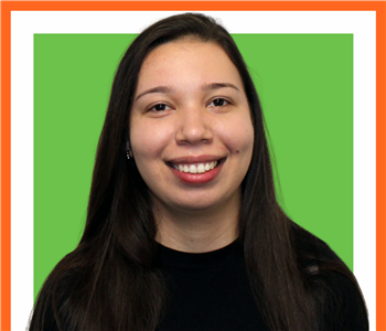 female employee with long black hair under green SERVPRO sign