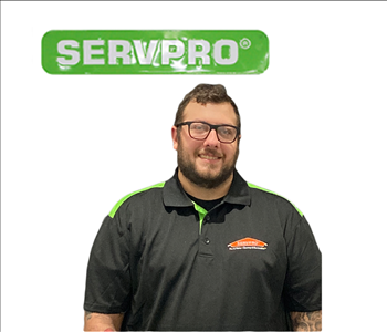 Joseph Copeland posing against white background underneath a green SERVPRO® sign