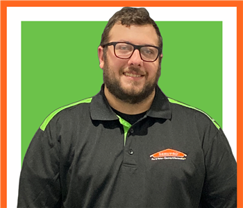 Joseph Copeland posing against white background underneath a green SERVPRO® sign