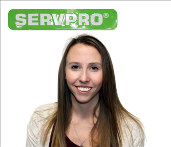 Female employee with long blonde hair standing under green SERVPRO sign