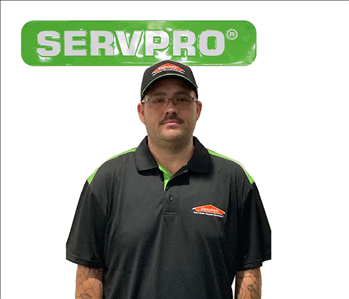 Michael Harrison standing in front of white wall underneath a green and white SERVPRO sign