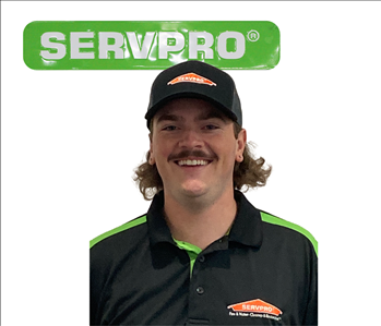 Cooper, Servpro employee, male, wearing a uniform in front of a white background and green SERVPRO sign