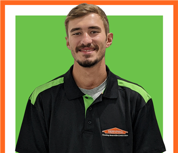 Kyle Greene posing against white background underneath a green SERVPRO® sign